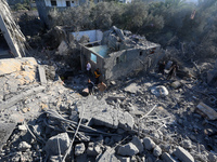 Palestinians gather on the rubble of a house destroyed in an Israeli strike at the Nuseirat refugee camp in the central Gaza Strip on Novemb...