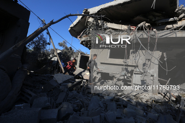 Palestinians gather on the rubble of a house destroyed in an Israeli strike at the Nuseirat refugee camp in the central Gaza Strip on Novemb...