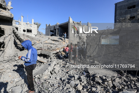 Palestinians gather on the rubble of a house destroyed in an Israeli strike at the Nuseirat refugee camp in the central Gaza Strip on Novemb...