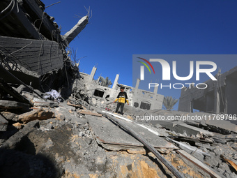 A Palestinian boy walks on the rubble of a house destroyed in an Israeli strike at the Nuseirat refugee camp in the central Gaza Strip on No...