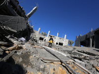 A Palestinian boy walks on the rubble of a house destroyed in an Israeli strike at the Nuseirat refugee camp in the central Gaza Strip on No...