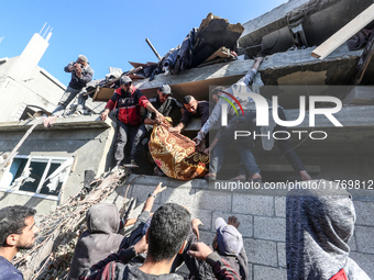 A body of a Palestinian is retrieved from the rubble of a house destroyed in an Israeli strike at the Nuseirat refugee camp in the central G...