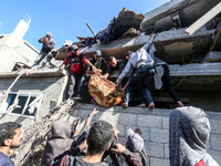 A body of a Palestinian is retrieved from the rubble of a house destroyed in an Israeli strike at the Nuseirat refugee camp in the central G...