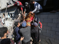 A body of a Palestinian is retrieved from the rubble of a house destroyed in an Israeli strike at the Nuseirat refugee camp in the central G...