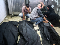 People react next to the bodies of Palestinians killed in an Israeli airstrike at the Al-Aqsa Martyrs Hospital in Deir al-Balah, central Gaz...