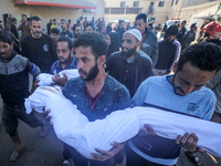 People carry the bodies of two children killed in an Israeli airstrike to the Al-Aqsa Martyrs Hospital in Deir al-Balah, central Gaza Strip,...