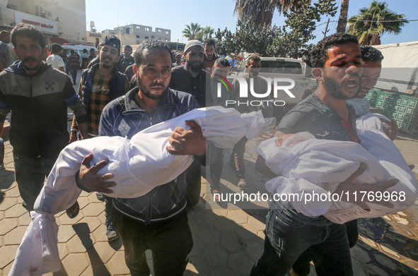 People carry the bodies of two children killed in an Israeli airstrike to the Al-Aqsa Martyrs Hospital in Deir al-Balah, central Gaza Strip,...