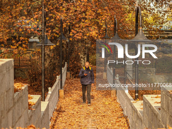 A man walks over a wooden bridge during an autumn day in Srinagar, Jammu and Kashmir, on November 12, 2024. Autumn, locally known as Harud,...