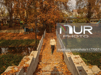 A man walks over a wooden bridge during an autumn day in Srinagar, Jammu and Kashmir, on November 12, 2024. Autumn, locally known as Harud,...