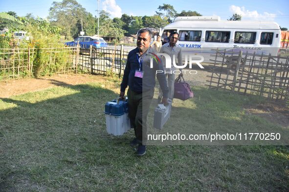 An election official carries electronic materials to a polling station on the eve of the Assam state assembly by-elections in Samaguri, Naga...