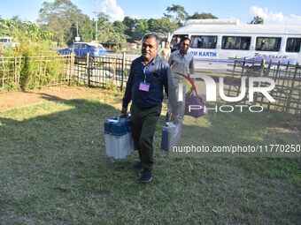 An election official carries electronic materials to a polling station on the eve of the Assam state assembly by-elections in Samaguri, Naga...