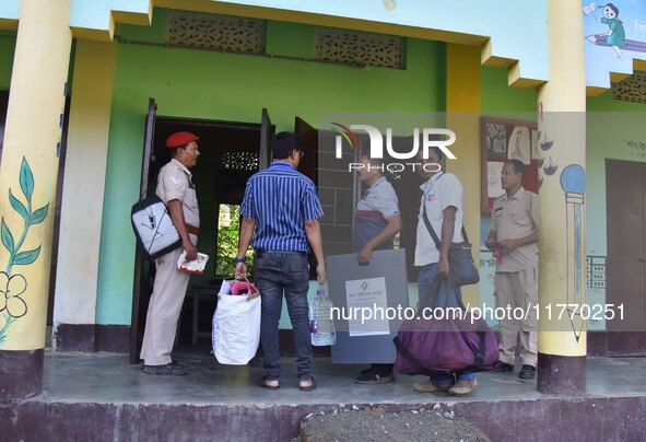 An election official carries electronic materials to a polling station on the eve of the Assam state assembly by-elections in Samaguri, Naga...