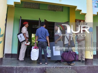 An election official carries electronic materials to a polling station on the eve of the Assam state assembly by-elections in Samaguri, Naga...