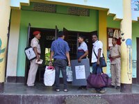 An election official carries electronic materials to a polling station on the eve of the Assam state assembly by-elections in Samaguri, Naga...