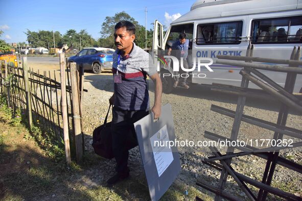 An election official carries electronic materials to a polling station on the eve of the Assam state assembly by-elections in Samaguri, Naga...