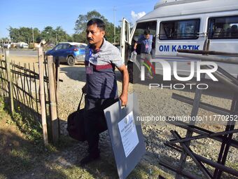 An election official carries electronic materials to a polling station on the eve of the Assam state assembly by-elections in Samaguri, Naga...