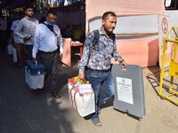 Officials carry Electronic Voting Machines (EVM) to their polling stations on the eve of Assam state assembly by-elections in Nagaon Distric...