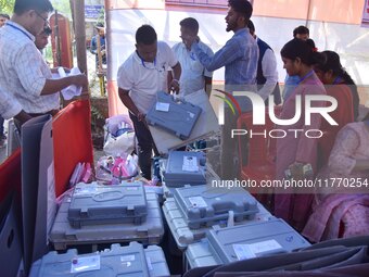 Election officials check Electronic Voting Machines (EVMs) and other polling materials at a distribution center in Nagaon District, Assam, I...