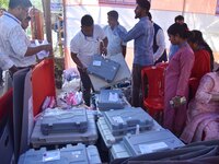 Election officials check Electronic Voting Machines (EVMs) and other polling materials at a distribution center in Nagaon District, Assam, I...