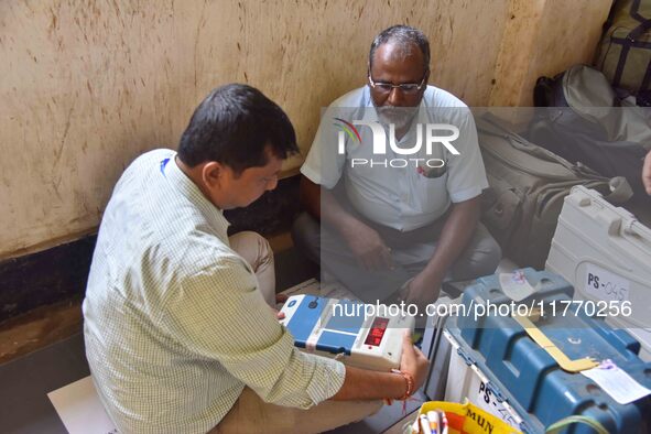 Polling officials check Electronic Voting Machines (EVMs) and other polling materials after receiving them from a distribution center on the...