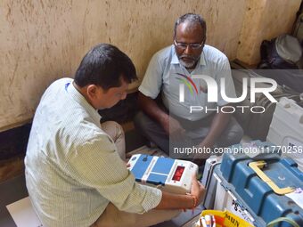 Polling officials check Electronic Voting Machines (EVMs) and other polling materials after receiving them from a distribution center on the...