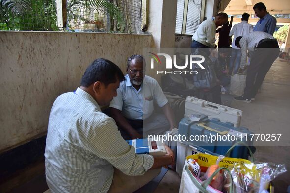 Polling officials check Electronic Voting Machines (EVMs) and other polling materials after receiving them from a distribution center on the...