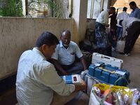 Polling officials check Electronic Voting Machines (EVMs) and other polling materials after receiving them from a distribution center on the...