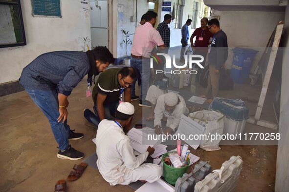 Polling officials check Electronic Voting Machines (EVMs) and other polling materials after receiving them from a distribution center on the...