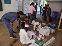 Polling officials check Electronic Voting Machines (EVMs) and other polling materials after receiving them from a distribution center on the...