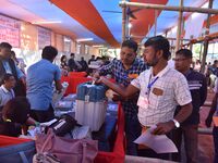 Polling officials receive Electronic Voting Machines (EVMs) and other polling materials from a distribution center in Nagaon District, Assam...