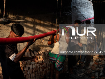 Local people help with the water pipe of the fire service to extinguish the fire at a shoe factory in the Shyampur area in Dhaka, Bangladesh...