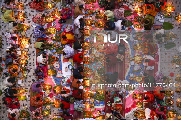 Hindu devotees sit together in front of oil lamps and candles and pray to Lokenath Brahmachari, a Hindu saint and philosopher, as they obser...