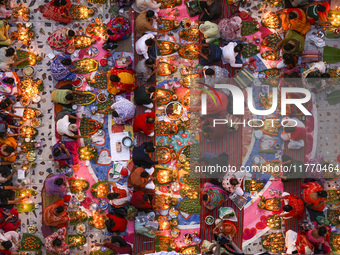 Hindu devotees sit together in front of oil lamps and candles and pray to Lokenath Brahmachari, a Hindu saint and philosopher, as they obser...