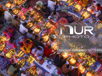 Hindu devotees sit together in front of oil lamps and candles and pray to Lokenath Brahmachari, a Hindu saint and philosopher, as they obser...