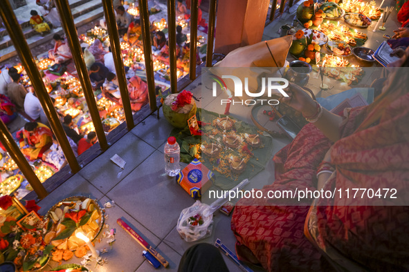 Hindu devotees sit together in front of oil lamps and candles and pray to Lokenath Brahmachari, a Hindu saint and philosopher, as they obser...