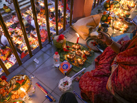 Hindu devotees sit together in front of oil lamps and candles and pray to Lokenath Brahmachari, a Hindu saint and philosopher, as they obser...