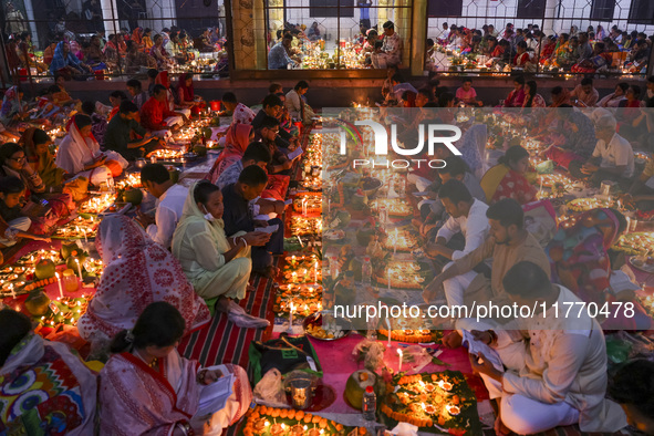 Hindu devotees sit together in front of oil lamps and candles and pray to Lokenath Brahmachari, a Hindu saint and philosopher, as they obser...