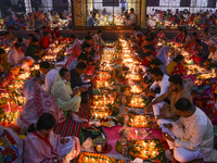 Hindu devotees sit together in front of oil lamps and candles and pray to Lokenath Brahmachari, a Hindu saint and philosopher, as they obser...