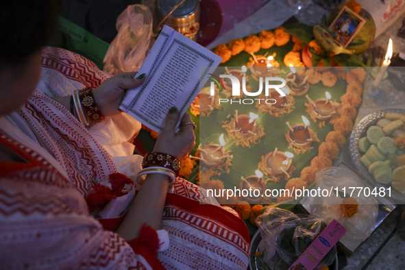 Hindu devotees sit together in front of oil lamps and candles and pray to Lokenath Brahmachari, a Hindu saint and philosopher, as they obser...