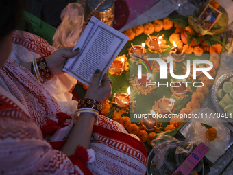 Hindu devotees sit together in front of oil lamps and candles and pray to Lokenath Brahmachari, a Hindu saint and philosopher, as they obser...