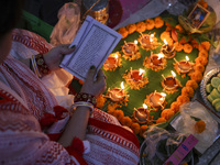 Hindu devotees sit together in front of oil lamps and candles and pray to Lokenath Brahmachari, a Hindu saint and philosopher, as they obser...