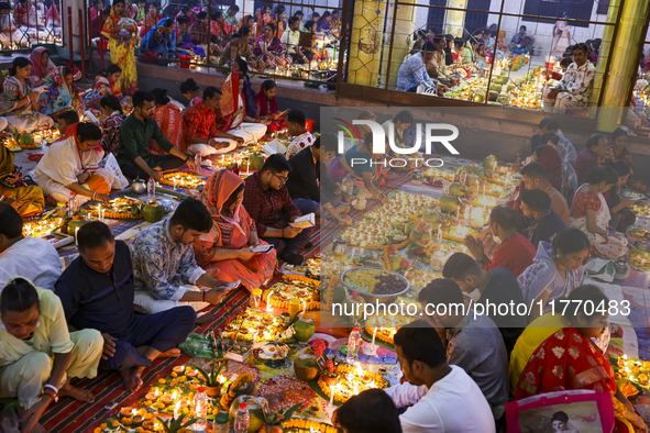 Hindu devotees sit together in front of oil lamps and candles and pray to Lokenath Brahmachari, a Hindu saint and philosopher, as they obser...