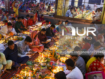 Hindu devotees sit together in front of oil lamps and candles and pray to Lokenath Brahmachari, a Hindu saint and philosopher, as they obser...