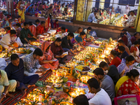 Hindu devotees sit together in front of oil lamps and candles and pray to Lokenath Brahmachari, a Hindu saint and philosopher, as they obser...