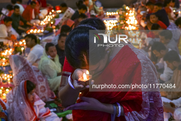 Hindu devotees sit together in front of oil lamps and candles and pray to Lokenath Brahmachari, a Hindu saint and philosopher, as they obser...