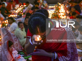 Hindu devotees sit together in front of oil lamps and candles and pray to Lokenath Brahmachari, a Hindu saint and philosopher, as they obser...