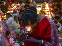 Hindu devotees sit together in front of oil lamps and candles and pray to Lokenath Brahmachari, a Hindu saint and philosopher, as they obser...