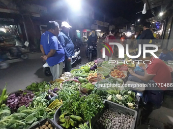 People buy vegetables at an evening market in Siliguri, India, on November 12, 2024. Vegetable and onion prices soar in the market. (