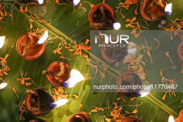 Hindu devotees sit together in front of oil lamps and candles and pray to Lokenath Brahmachari, a Hindu saint and philosopher, as they obser...