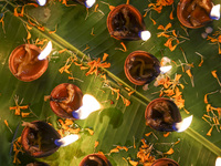 Hindu devotees sit together in front of oil lamps and candles and pray to Lokenath Brahmachari, a Hindu saint and philosopher, as they obser...